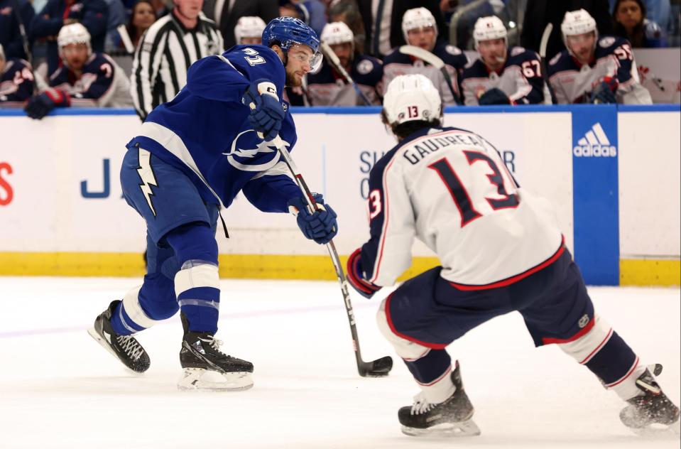Apr 9, 2024; Tampa, Florida, USA; Tampa Bay Lightning center Anthony Cirelli (71) shoots as Columbus Blue Jackets left wing Johnny Gaudreau (13) defends during the first period at Amalie Arena. Mandatory Credit: Kim Klement Neitzel-USA TODAY Sports