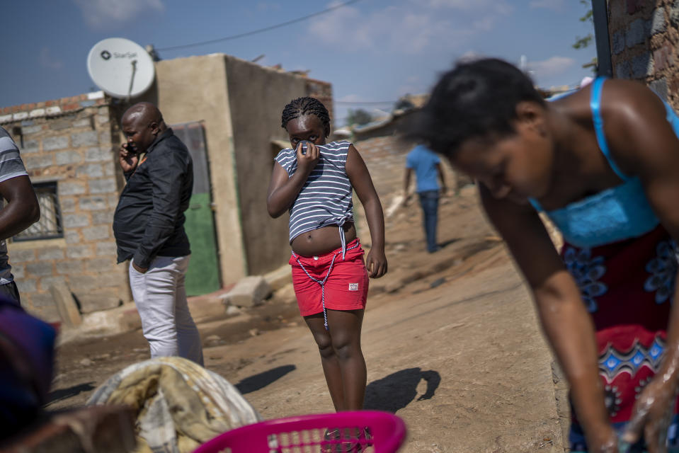 A young girl covers her face, in the Sjwetla informal settlement on the outskirt of the Alexandra township in Johannesburg, May 5, 2020, during the coronavirus outbreak. (AP Photo/Jerome Delay)