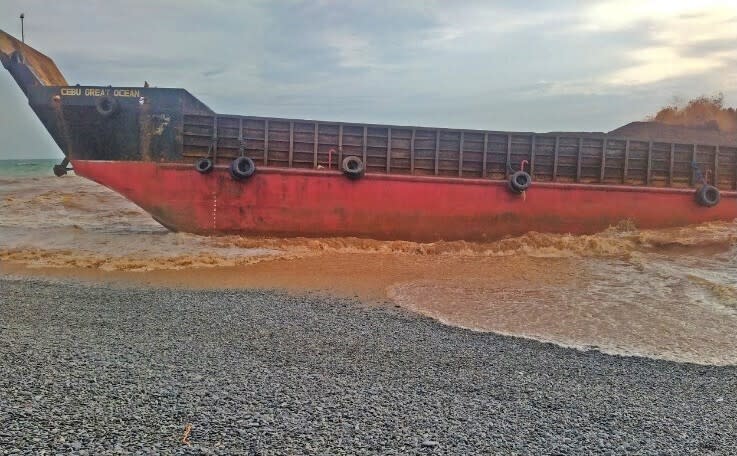 This photo provided by the Philippine Coast Guard shows the cargo vessel LCT Cebu Great Ocean aground along the shoreline of Barangay Cantapoy, Malimono, Surigao del Norte, southern Philippines on Monday April 19, 2021. Rescuers in the southern Philippines found the bodies of four crew members Wednesday and rescued several others who jumped off a cargo vessel, which took in water and listed after its anchor broke in rough seas, officials said. (Philippine Coast Guard via AP)