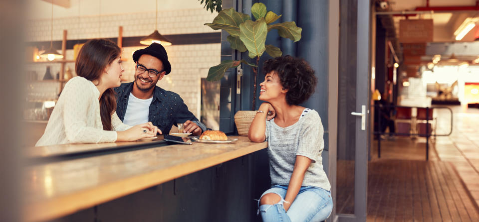 Portrait of three young people sitting together at a cafe. Group of young friends meeting in a coffee shop.