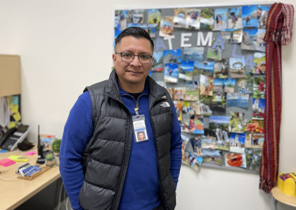 Mountain View Elementary School parent educator Ted Pedro stands in his office, his wall decorated with a collage made from pictures of a recent trip back home to Guatemala. (Burke County Public Schools)