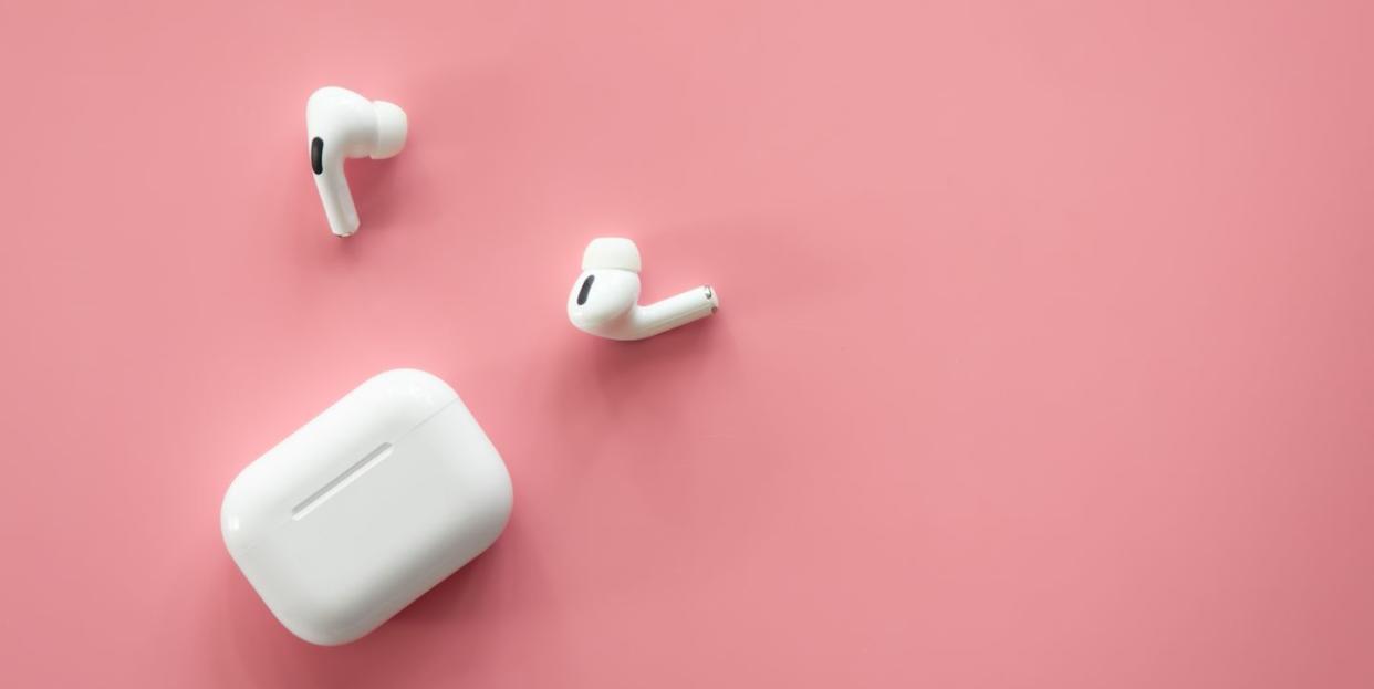 wireless in ear headphones with a case on a pink background, flat lay, conceptual minimalism