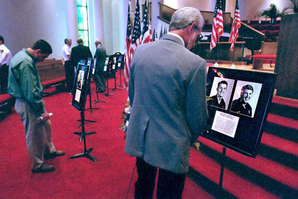 Stan Norket, the stepfather of slain police Officer John Burnette, reads the inscription below the photographs of Burnette (left) and his partner Anthony Nobles, at a Peace Officers memorial service for fallen officers Friday at First Baptist Church in Charlotte. T. ORTEGA GAINES