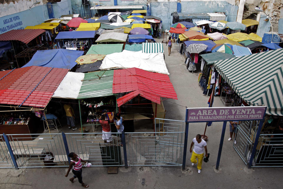 People walk in an open-air market where the government allows licensed vendors to sell their goods in Havana, Cuba, Friday, Aug. 31, 2012. The entrance sign reads in Spanish "Sales area for the self-employed." A jump in import taxes on Monday, Sept. 3 threatens to make life tougher for some of Cuba's new entrepreneurs who the government has been trying to encourage as it cuts a bloated workforce in the socialist economy. In Cuba, the average monthly wage is about $20. (AP Photo/Franklin Reyes)