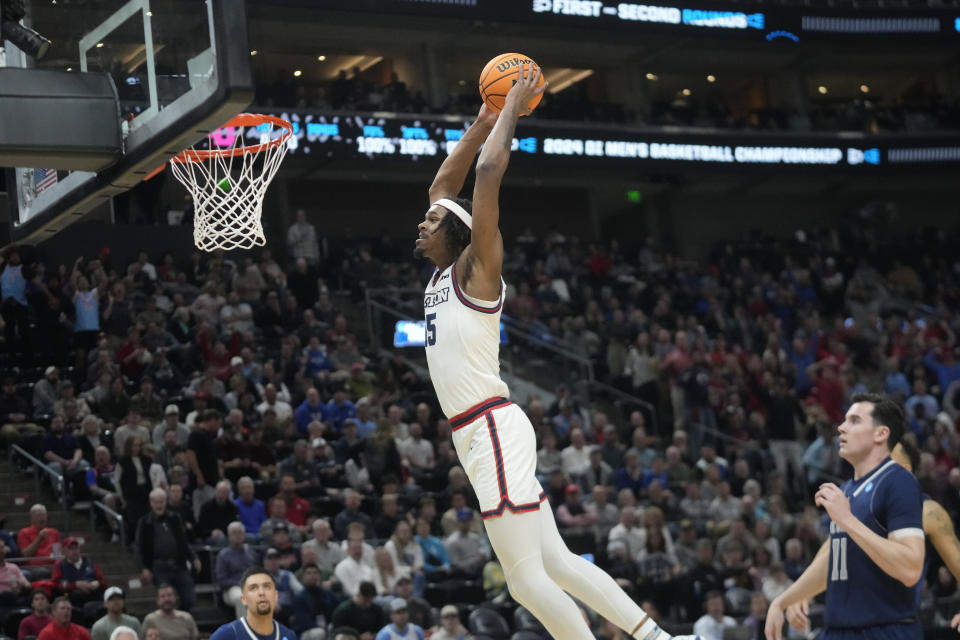 Nevada forward Nick Davidson (11) watches as Dayton forward DaRon Holmes II, top center, dunks during the first half of a first-round college basketball game in the NCAA Tournament in Salt Lake City, Thursday, March 21, 2024. (AP Photo/Rick Bowmer)