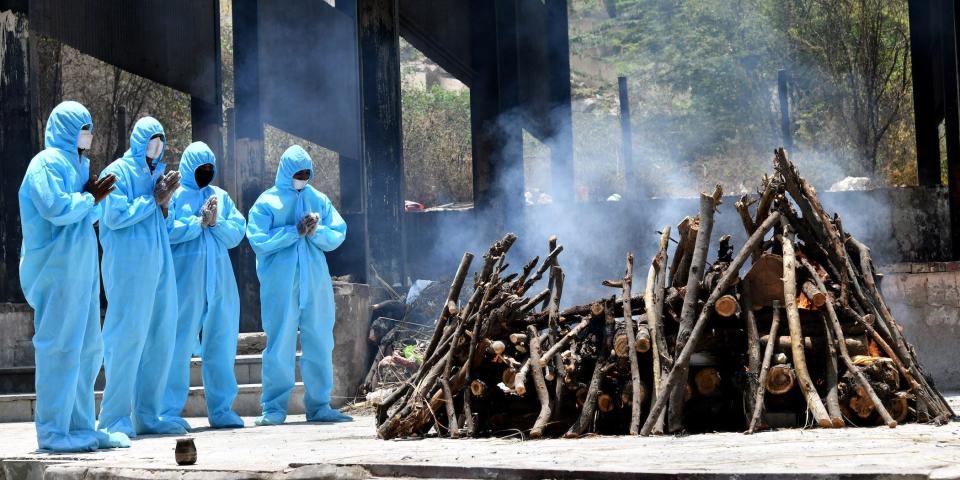 Relatives bow their heads and pray next to a cremation pyre for a relative who died of COVID-19.