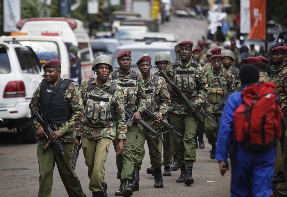 Kenyan security forces walk from the scene as continued blasts and gunfire could be heard early Wednesday, Jan. 16, 2019, in Nairobi, Kenya. Extremists stormed a luxury hotel in Kenya's capital on Tuesday, setting off thunderous explosions and gunning down people at cafe tables in an attack claimed by Africa's deadliest Islamic militant group. (AP Photo/Ben Curtis)