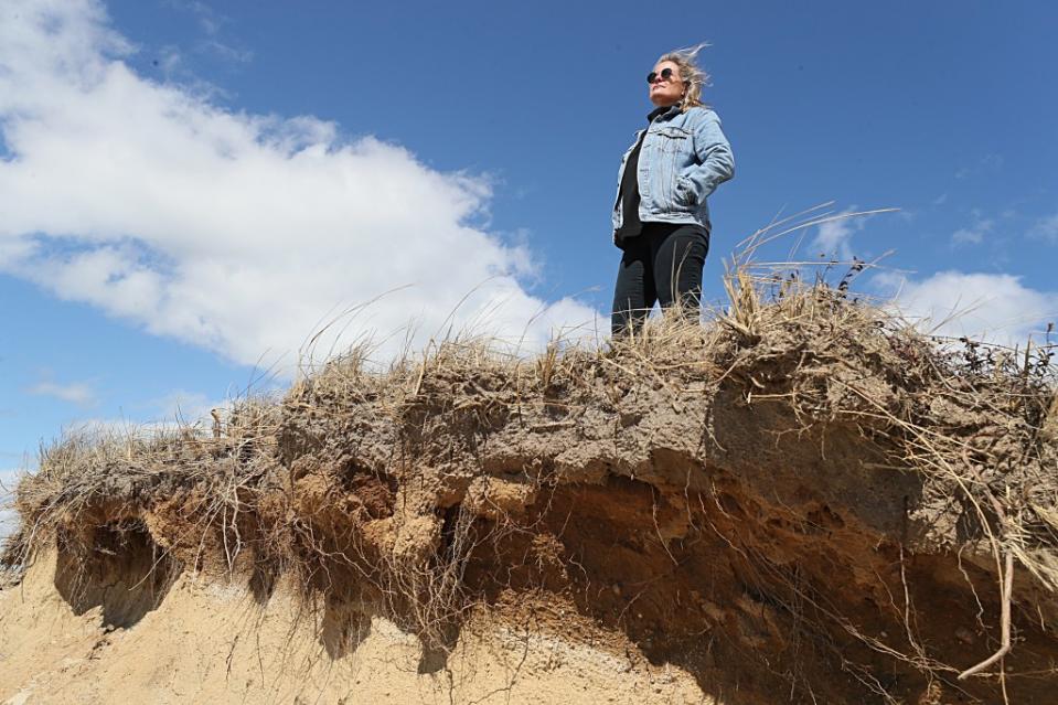 Shelly Lockwood stands on a beach in Madaket near Clark Cove where coastal erosion is evident. Boston Globe via Getty Images