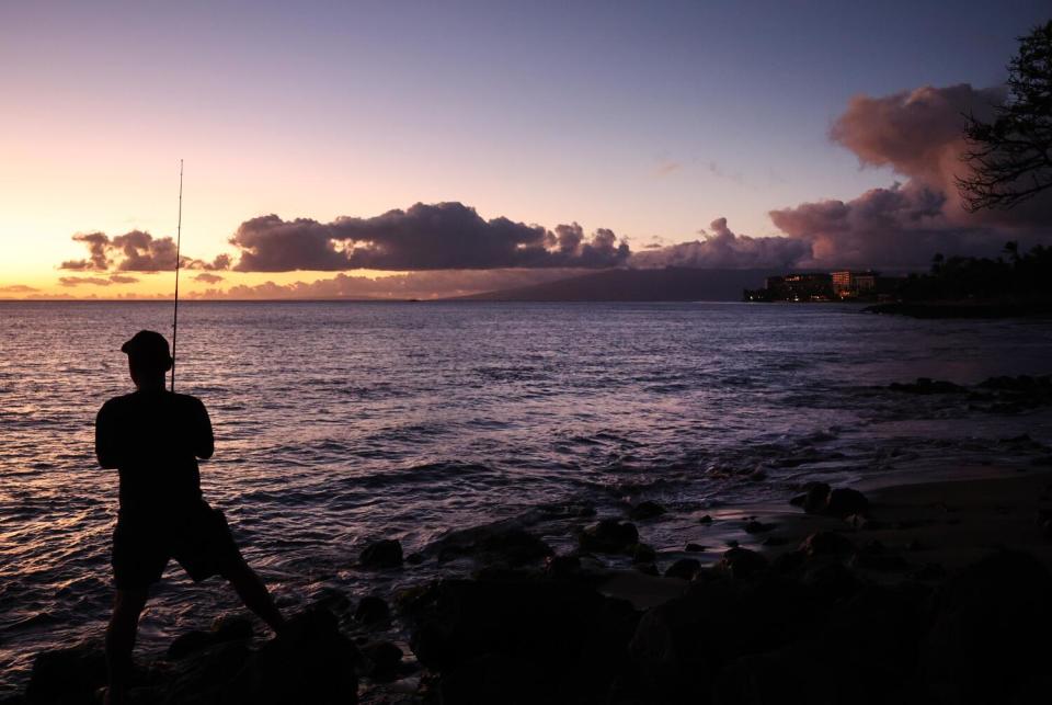 A resident fishes with resort properties in the distance