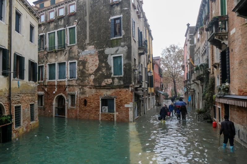 People walk outside during exceptionally high water levels in Venice