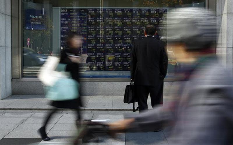 A pedestrian looks at a stock quotation board outside a brokerage in Tokyo November 26, 2013. REUTERS/Yuya Shino