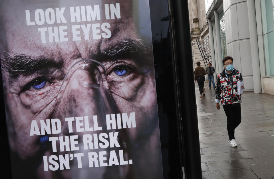 A man wearing a mask against coronavirus walks past an NHS advertisement about COVID-19 in London, Tuesday, Feb. 2, 2021. British health authorities plan to test tens of thousands of people in a handful of areas of England in an attempt to stop a new variant of the coronavirus first identified in South Africa spreading in the community. The Department of Health says a small number of people in England who had not travelled abroad have tested positive for the strain. (AP Photo/Alastair Grant)