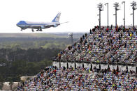 Race fans watch from the grandstands as Air Force One circles the Daytona International Speedway as President Donald Trump makes his arrival to attend the NASCAR Daytona 500 auto race at Daytona International Speedway, Sunday, Feb. 16, 2020, in Daytona Beach, Fla. (AP Photo/Jim Topper)