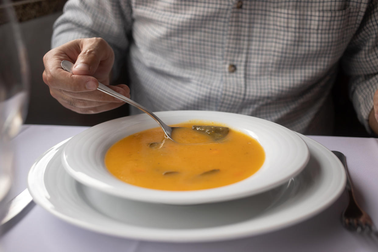 man eating vegetable soup in the restaurante�