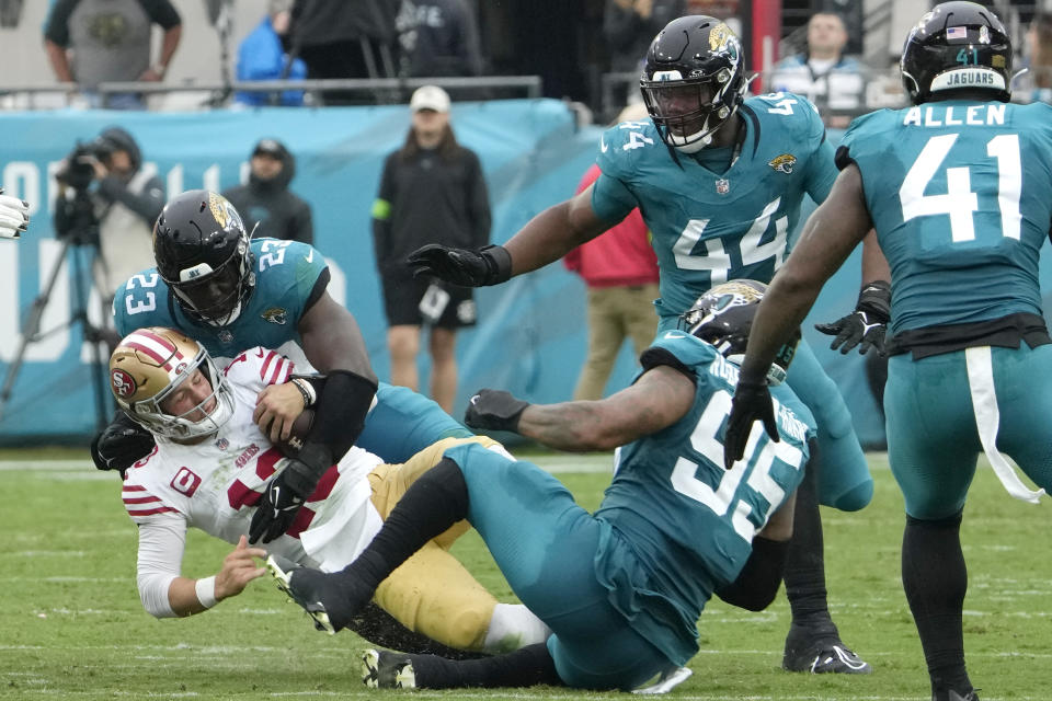 San Francisco 49ers quarterback Brock Purdy (13) is tackled by Jacksonville Jaguars linebacker Foyesade Oluokun (23) and defensive end Roy Robertson-Harris (95) during the second half of an NFL football game, Sunday, Nov. 12, 2023, in Jacksonville, Fla. (AP Photo/John Raoux)