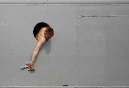 A Russian sailor cleans the navy ship Admiral Vinogradov from a porthole of the vessel during a port visit in Manila, Philippines October 20, 2017. REUTERS/Dondi Tawatao