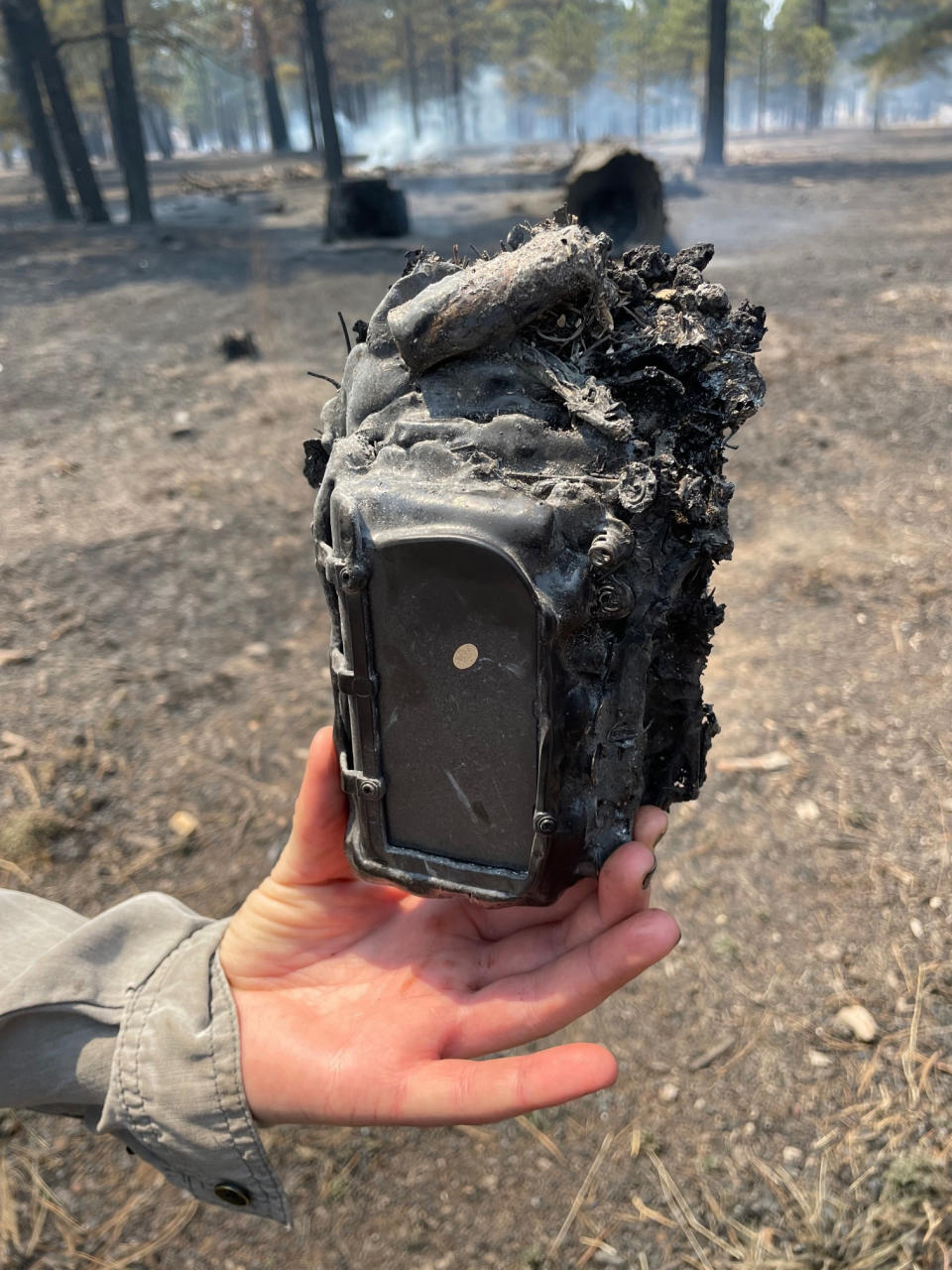 In this photo provided by the National Park Service, the remains of a ranger's game camera are held after the Tunnel Fire burned near the Sunset Crater Volcano National Monument in Arizona, Wednesday, April 20, 2022. Winds are expected to intensify through the end of the week as firefighters battle blazes across the Southwest. Resources are tight, and fire managers are scrambling to get crews on board. (Richard Ullman/National Park Service via AP)