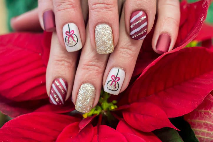holiday inspired art on nails with painted stripes and glitter polish and ornaments painted on
