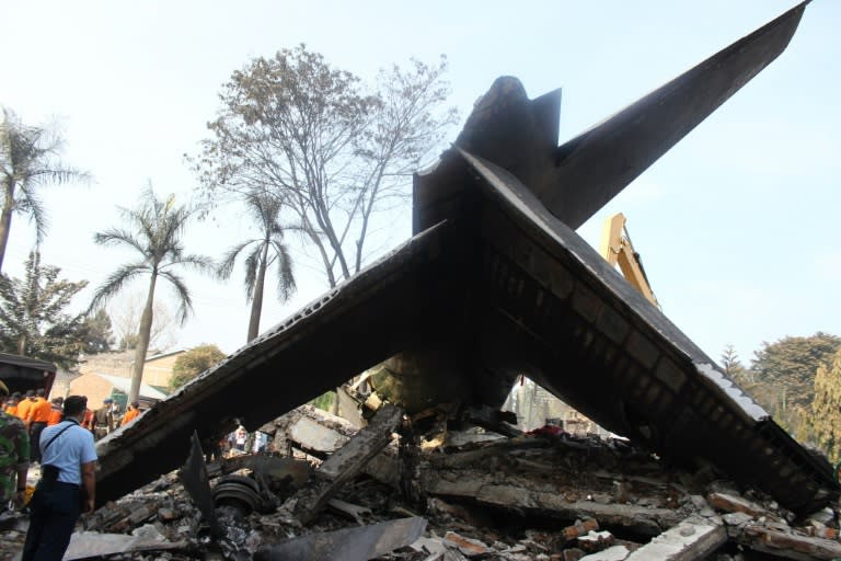 Soldiers search the tail and wreckage of an Indonesian Air Force C-130 Hercules aircraft on July 1, 2015, a day after it crashed into a neighbourhood in Medan city