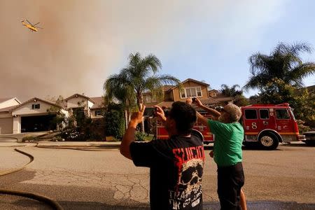 People take pictures of a firefighting helicopter during the so-called Sand Fire in the Angeles National Forest near Los Angeles, California, U.S. July 24, 2016. REUTERS/Jonathan Alcorn