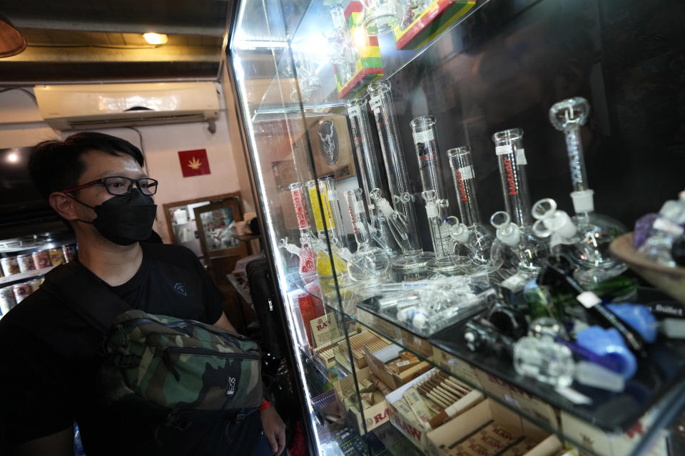 A customer views an array of paraphernalia used to smoke marijuana at the Highland Cafe in Bangkok, Thailand, Thursday, June 9, 2022. Measures to legalize cannabis became effective Thursday, paving the way for medical and personal use of all parts of cannabis plants, including flowers and seeds. (AP Photo/Sakchai Lalit)