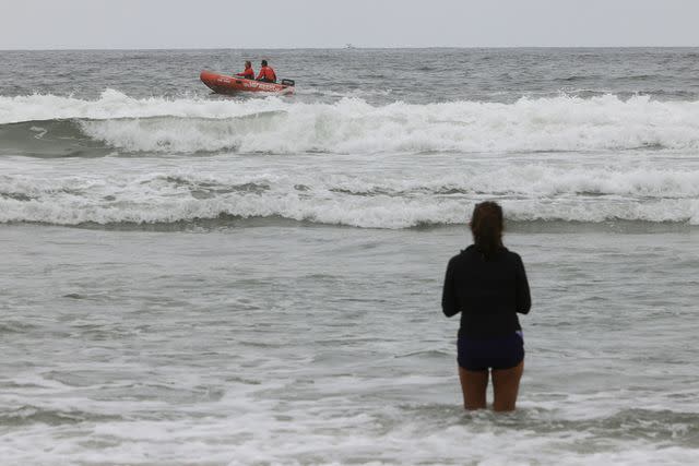 <p>Hayne Palmour IV/Shutterstock</p> Woman watches lifeguards pass by on a boat in Del Mar, Calif.