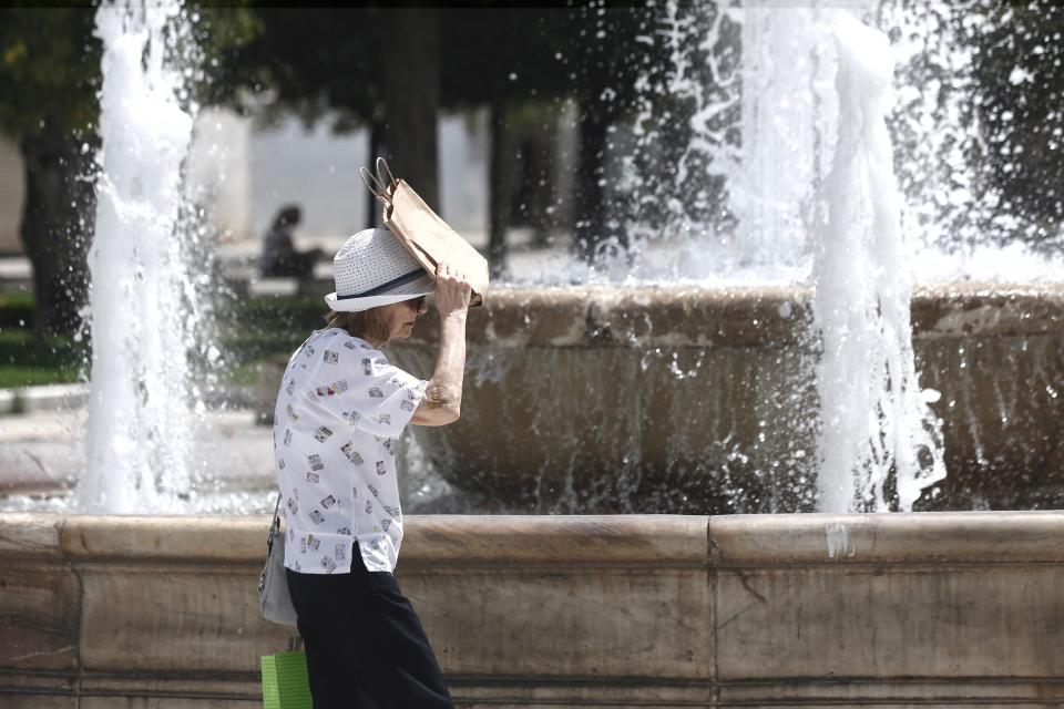 A woman protects herself from the sun while walking in Greece (EPA)