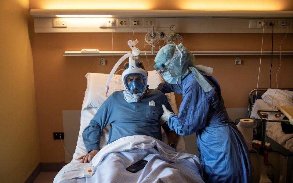 A nurse helps a patient wearing a full-face snorkeling face mask converted into a breathing device in the Maria Pia Hospital in Turin  - AFP