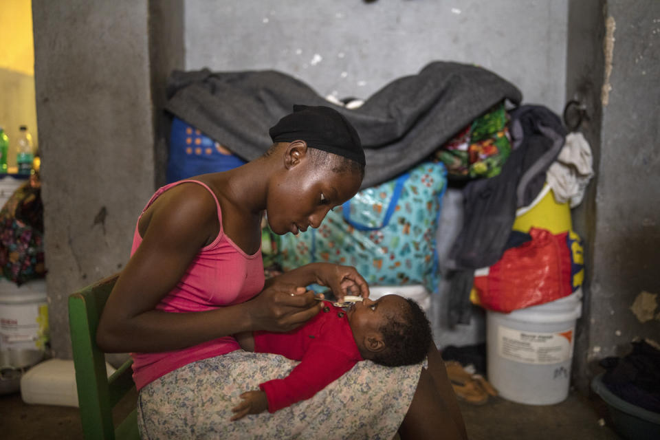 A woman feeds her infant son in a shelter for internally displaced people due to violence, at a school converted into a shelter, in Port-au-Prince, Haiti, Tuesday, Sept. 14, 2021. Officials say the gangs' fight over territory in Port-au-Prince has forced hundreds of families to abandon burned or ransacked homes in impoverished communities, with many of them staying in gymnasiums and other temporary shelters that are running out of water, food and items like blankets and clothes. (AP Photo/Rodrigo Abd)