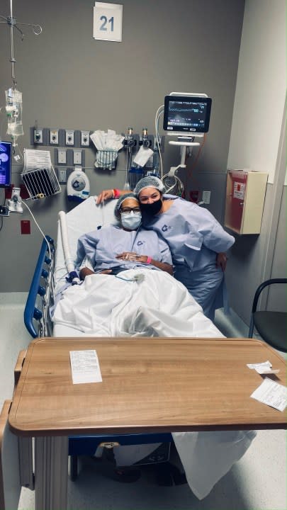 
woman in hospital gown poses with another woman in hospital bed        