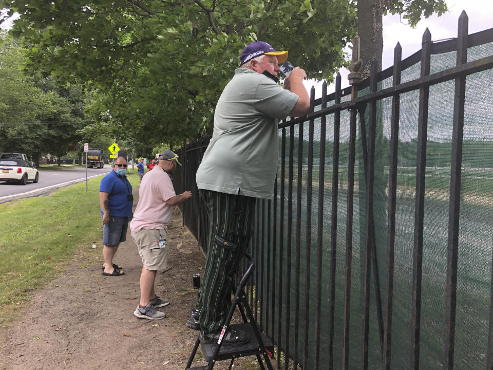 A fan uses a step-stool so he can see horse racing action above the fence at the Saratoga Race Course in Saratoga Springs, N.Y. , Thursday, July 16, 2020. A Saratoga season like no other is open, with fans barred from attending the start of the 152nd meet in track history and most likely the entire 40 days of racing. (AP Photo/John Kekis)