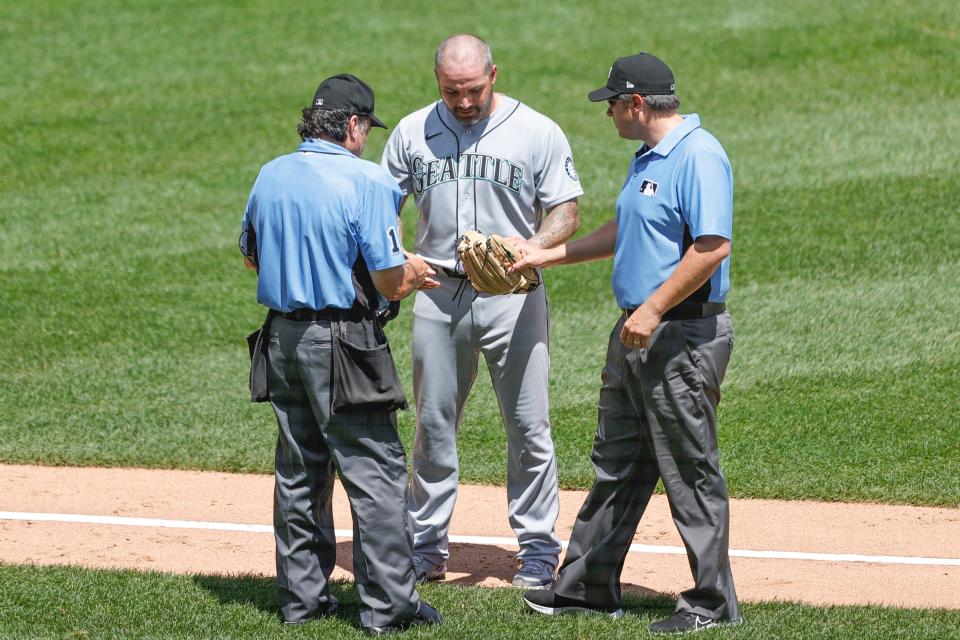 Umpires Phil Cuzzi and Mark Ripperger check Mariners relief pitcher Hector Santiago's glove for illegal substance.