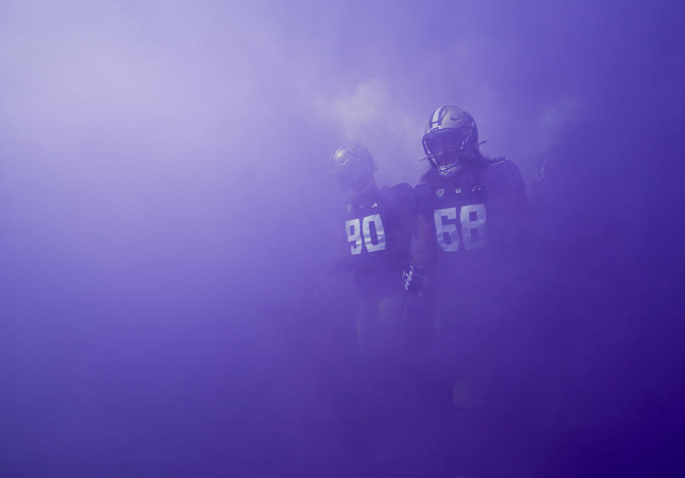 Washington defensive lineman Elinneus Davis (90) and offensive lineman Soane Faasolo (68) walk out through purple smoke before the team's NCAA college football game against Boise State, Saturday, Sept. 2, 2023, in Seattle. (AP Photo/Lindsey Wasson)