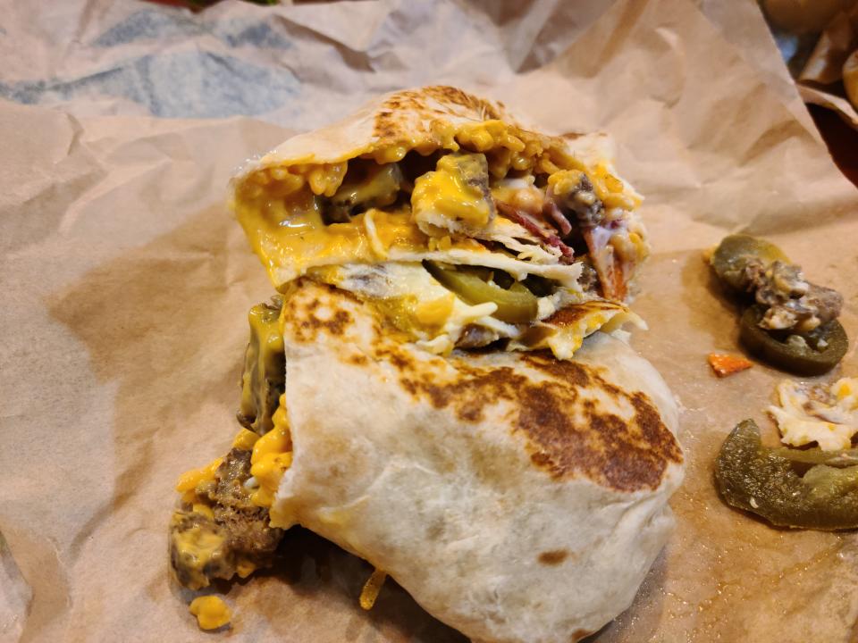 spicy double steak grilled cheese burrito from taco bell cut in half and resting on a paper wrapper