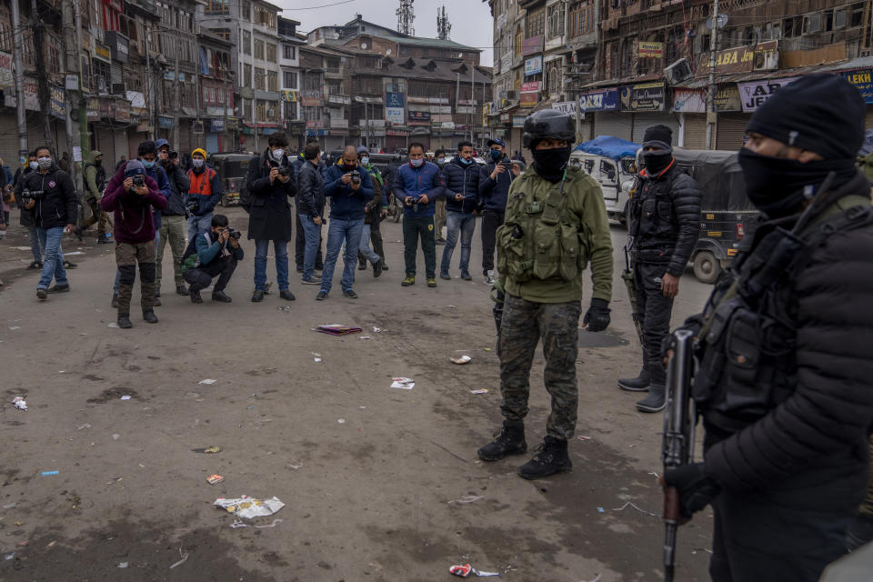 Kashmiri photojournalists work as soldiers stand guard during a surprise search of pedestrians by security forces in Srinagar, Indian controlled Kashmir, Friday, Jan. 21, 2022. Journalists in Indian-controlled Kashmir have long contended with threats and found themselves caught between the authorities and rebels. But their situation has gotten dramatically worse since India revoked the region’s semi-autonomy in 2019, throwing Kashmir under a security and communication lockdown. Journalists have been arrested, interrogated and investigated under harsh anti-terror laws. (AP Photo/Dar Yasin)