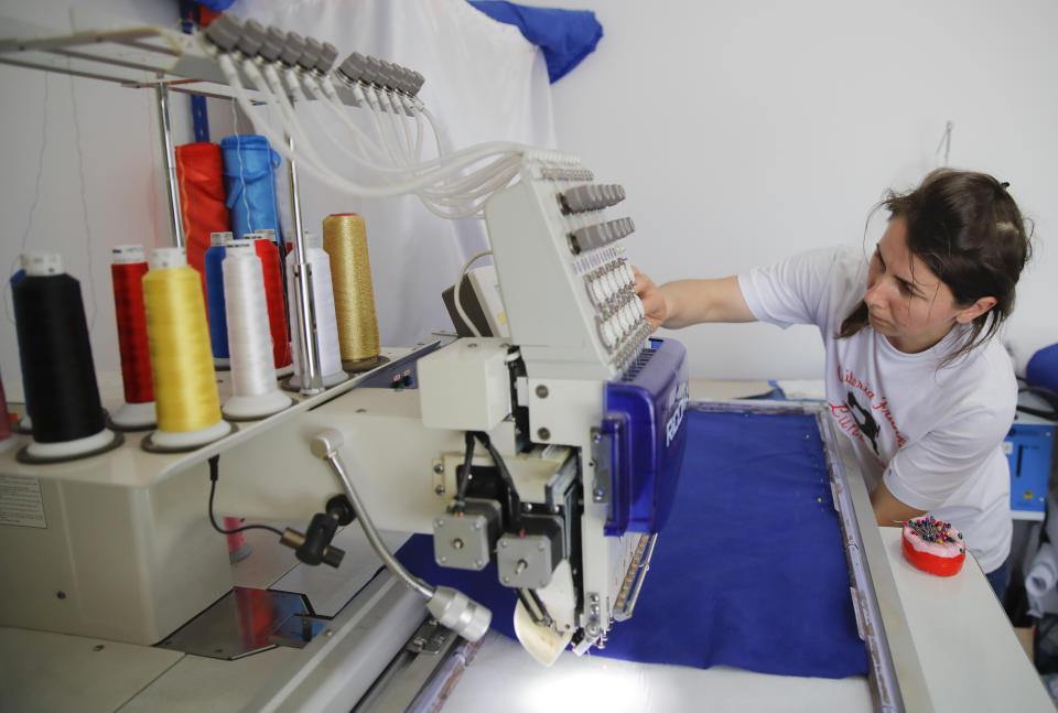 In this picture taken Tuesday, May 21, 2019, Valentina Radu works on an automated sewing machine in Luncavita, Romania. Radu also worked in Italy, but when her husband lost his job there, they struggled to pay the rent and decided to come home where they used European Union funds to buy a small farm and she further opened a tailor's shop. (AP Photo/Vadim Ghirda)