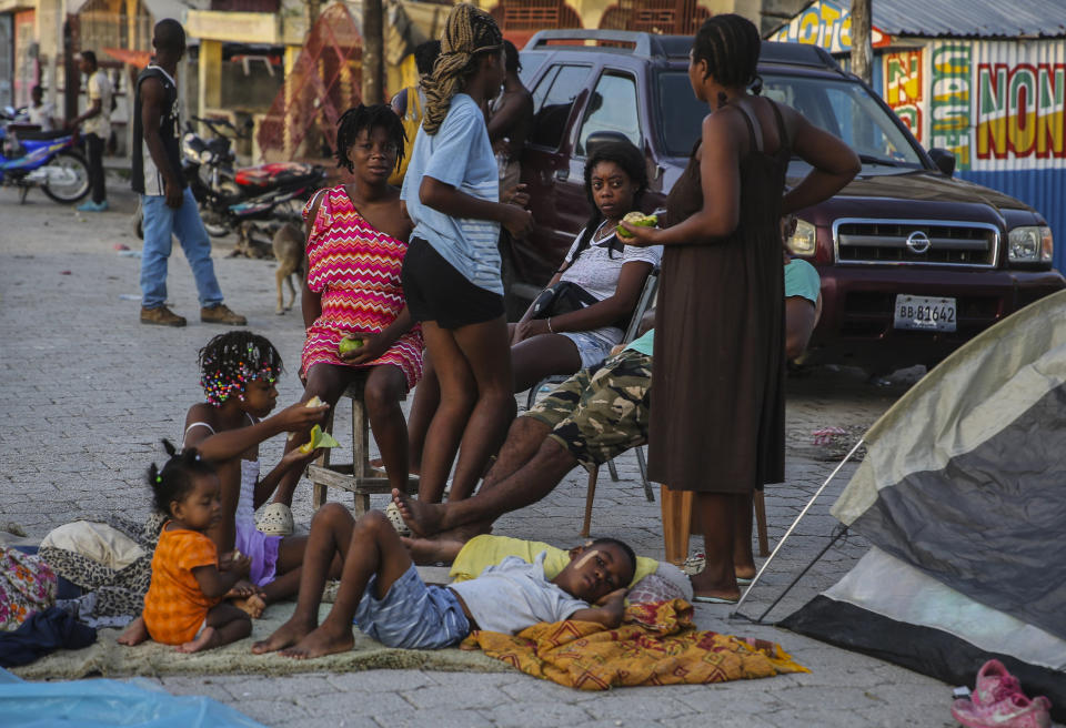 Locals eat after spending the night in the middle of a street after Saturday´s 7.2 magnitude earthquake in Les Cayes, Haiti, Sunday, Aug. 15, 2021. (AP Photo/Joseph Odelyn)