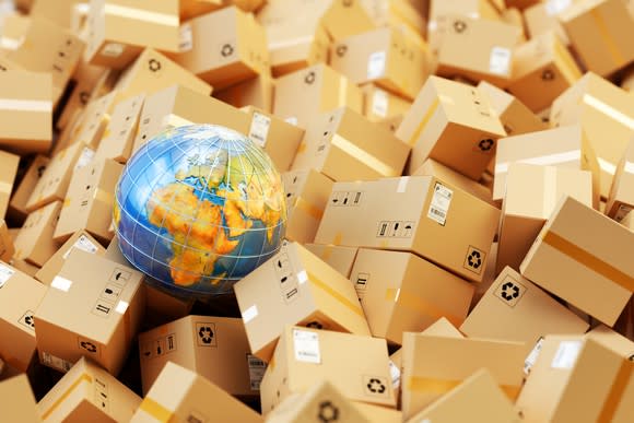 A heap of cardboard boxes and parcels around a globe.