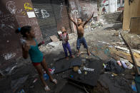 Children play near abandoned buildings, in an area recently occupied by squatters, in Rio de Janeiro, Brazil, Wednesday, April 9, 2014. Thousands of people have laid claim to a compound of abandoned office buildings owned by the private telecommunications company Oi, and named their settlement after the state-owned telecommunications Telerj. Authorities are negotiating with squatters to leave peacefully from the area they have occupied for more than a week. (AP Photo/Silvia Izquierdo)