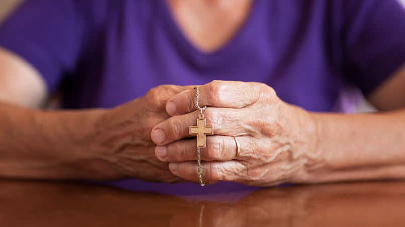 bible verses about anxiety woman with hands together holding a necklace with a cross