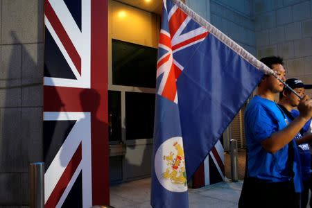 FILE PHOTO: A campaigner carries a former colonial Hong Kong flag while demanding Hong Kong-UK reunification protest outside the British Consulate on the day marking the 19th anniversary of Hong Kong's handover to Chinese sovereignty from British rule in Hong Kong, July 1, 2016. REUTERS/Bobby Yip/File Photo