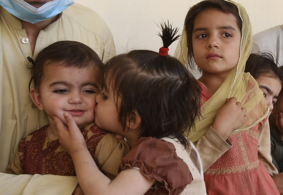 In this May 6, 2020 photo, Tariq Nawaz holds his 10-month-old baby daughter Tuba who suffers from polio, as a sister kisses her, in Suleiman Khel, Pakistan. For millions of people like Nawaz who live in poor and troubled regions of the world, the novel coronavirus is only the latest epidemic. They already face a plethora of fatal and crippling infectious diseases: polio, Ebola, cholera, dengue, tuberculosis and malaria, to name a few. The diseases are made worse by chronic poverty that leads to malnutrition and violence that disrupts vaccination campaigns. (AP Photo/Muhammad Sajjad)