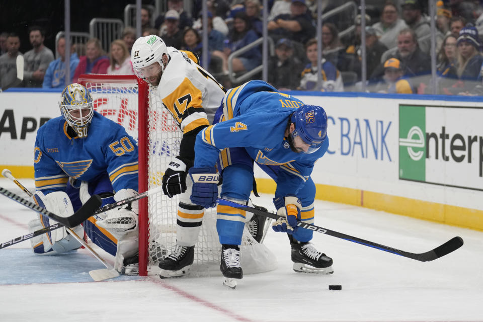 Pittsburgh Penguins' Bryan Rust (17) battles for a loose puck as St. Louis Blues goaltender Jordan Binnington (50) and Nick Leddy (4) defend during the first period of an NHL hockey game Saturday, Oct. 21, 2023, in St. Louis. (AP Photo/Jeff Roberson)