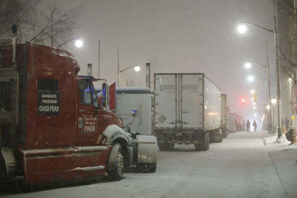 Protesters and supporters walk amongst trucks as they gather during a protest against COVID-19 measures that has grown into a broader anti-government protest that continues to occupy downtown Ottawa, Ontario, on Thursday, Feb. 17, 2022. (Cole Burston/The Canadian Press via AP)