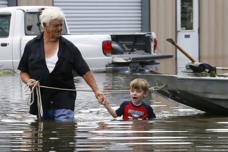 Richard Rossi and his 4 year old great grandson Justice wade through water in search of higher ground after their home took in water in St. Amant, Louisiana, U.S., August 15, 2016. REUTERS/Jonathan Bachman