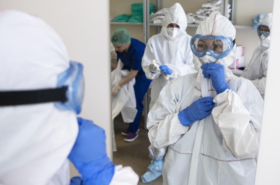 In this photo taken on Tuesday, April 21, 2020, medical workers put on protective gear in order to assist coronavirus patients at the intensive care unit of Vinogradov City Clinical Hospital in Moscow, Russia. Reports of Russian medical workers becoming infected with the coronavirus are emerging almost daily as the country copes with a growing number of patients. (AP Photo/Pavel Golovkin)