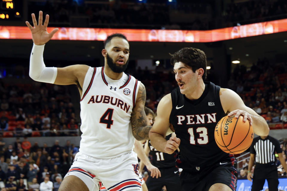 Penn forward Nick Spinoso (13) drives to the basket as Auburn forward Johni Broome (4) defends during the first half of an NCAA college basketball game Tuesday, Jan. 2, 2024, in Auburn, Ala. (AP Photo/Butch Dill)