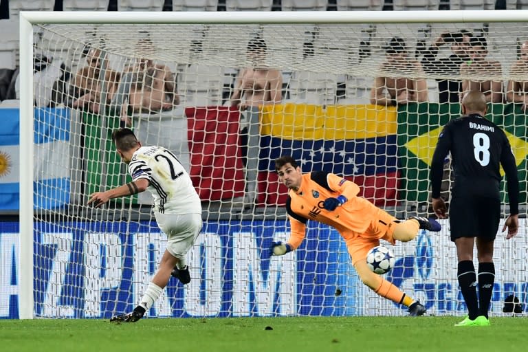 Juventus' forward Paulo Dybala (L) scores a penalty against Porto's goalkeeper Iker Casillas during their UEFA Champions League match on March 14, 2017 in Turin