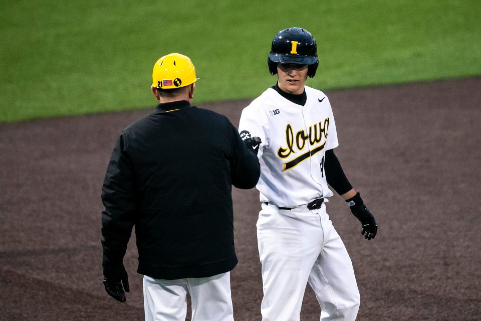 Iowa's Gehrig Christensen, right, bumps fists with head coach Rick Heller during an NCAA baseball game against Loras College on Feb. 28, 2023, at Duane Banks Field in Iowa City.