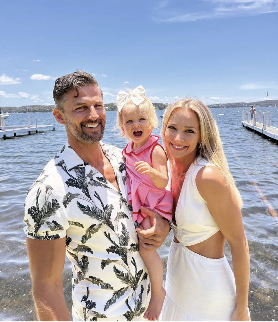 Tim Robards, Anna Heinrich and infant daughter Elle pose in front of the water